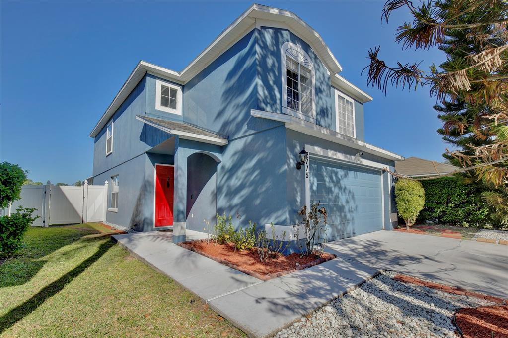 A two-story blue house with a red front door and an attached two-car garage — 2115 HEATHWOOD CIRCLE, ORLANDO, FL