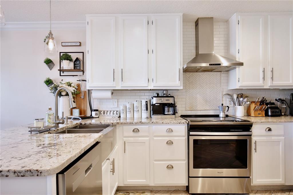 A bright kitchen features white cabinets, granite countertops, stainless steel appliances, and a farmhouse sink — 2115 HEATHWOOD CIRCLE, ORLANDO, FL