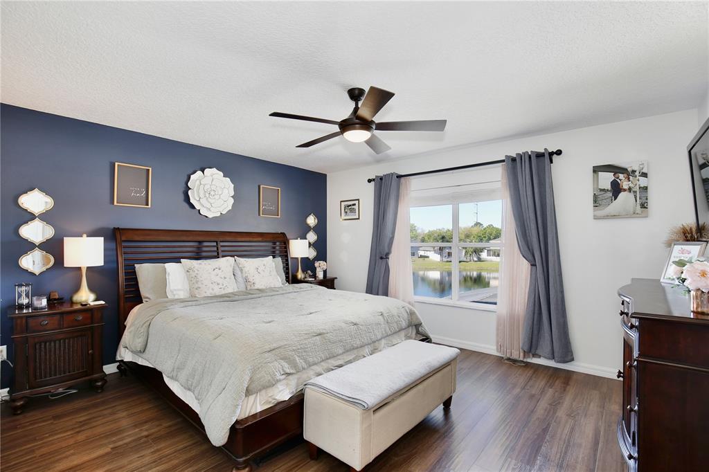 A bedroom features a dark blue accent wall, a wooden bed frame, and a lake view — 2115 HEATHWOOD CIRCLE, ORLANDO, FL