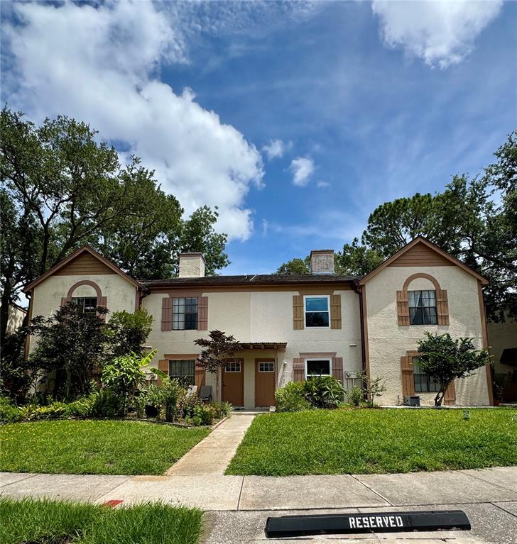 A two-story duplex with stucco siding, brown shutters, and a front walkway — 2504 BRIGADOON DRIVE, CLEARWATER, FL