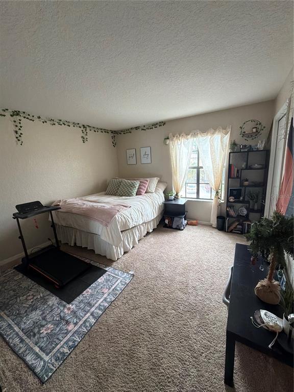A bedroom features a bed, a treadmill on a rug, and a tall shelving unit — 2504 BRIGADOON DRIVE, CLEARWATER, FL