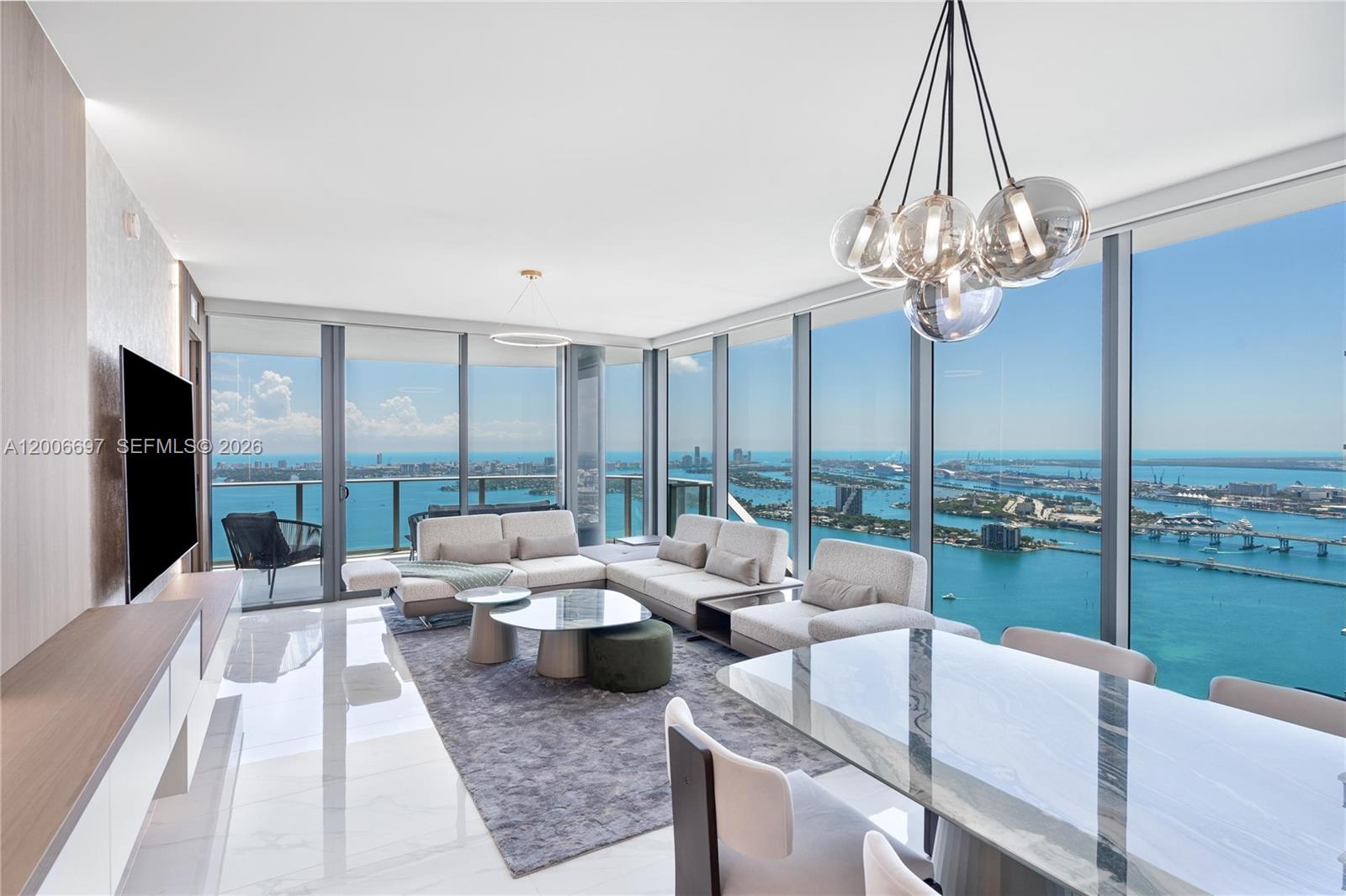 A modern living room features floor-to-ceiling windows with panoramic ocean and city skyline views — 700 NE 24th ST # 5407, Miami FL 33137, MIAMI, FL