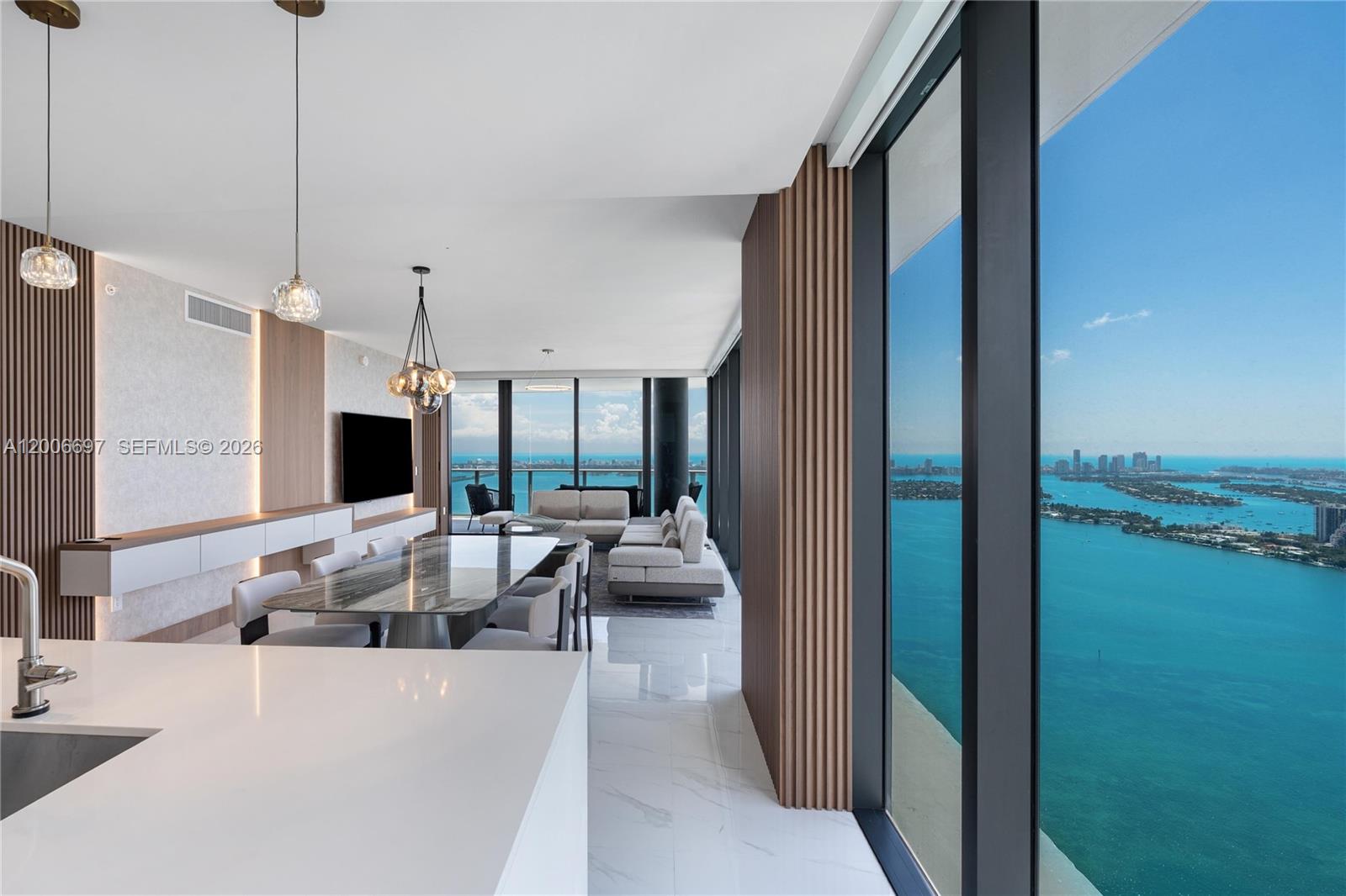 A modern open-concept living and dining area features floor-to-ceiling windows with expansive water views — 700 NE 24th ST # 5407, Miami FL 33137, MIAMI, FL