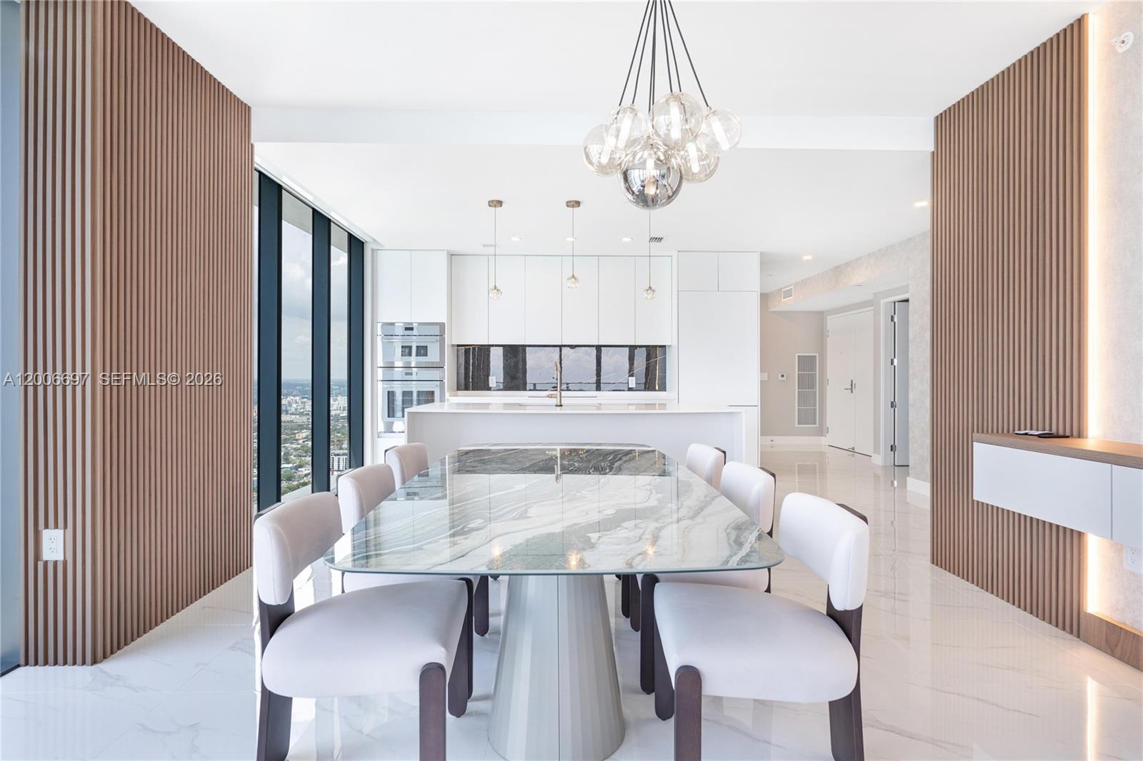 A modern dining room features a marble table, upholstered chairs, and wood-paneled accent walls — 700 NE 24th ST # 5407, Miami FL 33137, MIAMI, FL