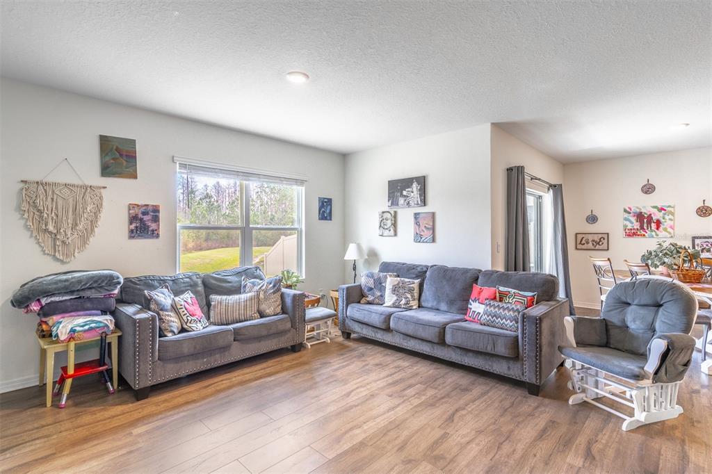 A living room features two gray sofas, a rocking chair, and wood-look flooring — 1419 FOX SQUIRREL DRIVE, DAVENPORT, FL