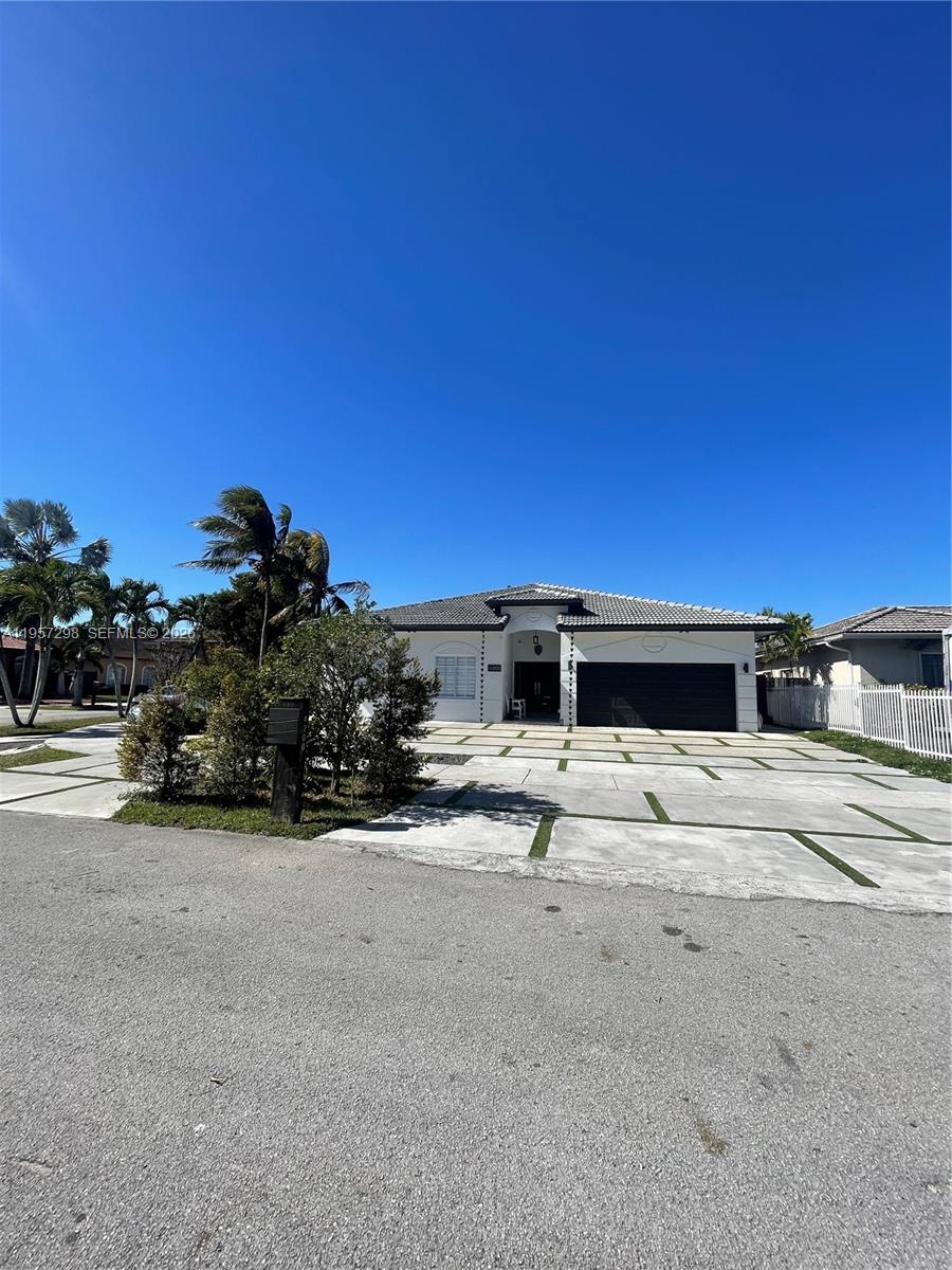A single-story house with a white exterior, a dark garage door, and a paved driveway — 14200 SW 160th Ct, Miami FL 33196, MIAMI, FL