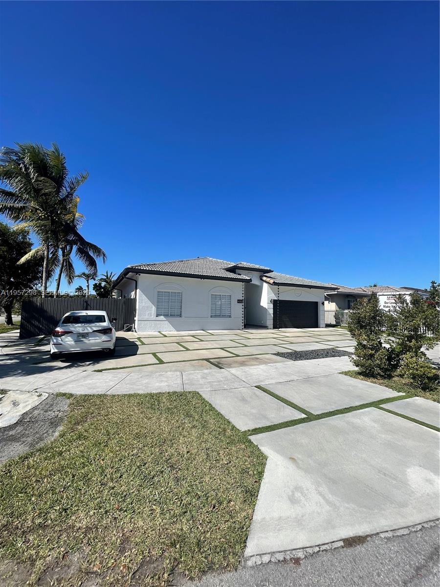 A white single-story house features a large concrete driveway with grass strips and a garage — 14200 SW 160th Ct, Miami FL 33196, MIAMI, FL
