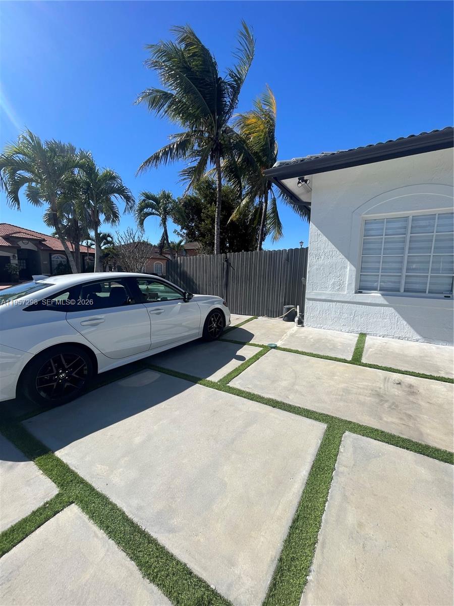 A white car is parked on a concrete driveway with grass strips beside a house — 14200 SW 160th Ct, Miami FL 33196, MIAMI, FL