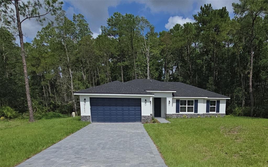A single-story house with a blue garage door, white siding, and a stone-accented base — 42021 TAMARAC STREET, EUSTIS, FL