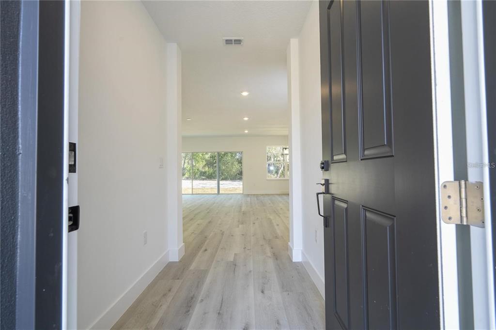 A view from an open front door into a hallway with light wood-look flooring — 42021 TAMARAC STREET, EUSTIS, FL