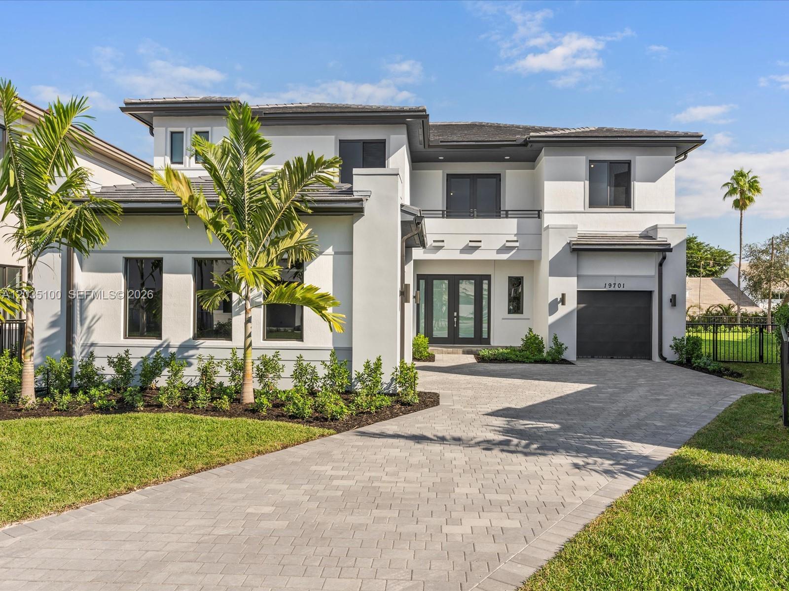 A modern two-story house features a paved driveway, a garage, and palm trees — 19701 NE 16th Pl, Miami FL 33179, MIAMI, FL