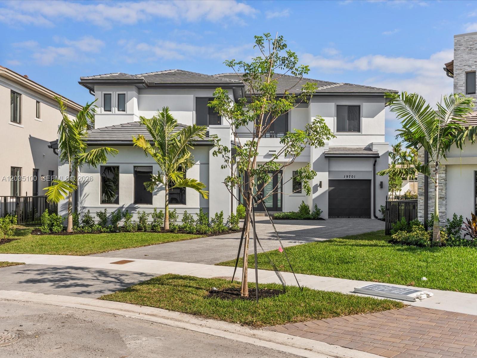A two-story modern house features a gray tiled roof, white stucco walls, and a driveway — 19701 NE 16th Pl, Miami FL 33179, MIAMI, FL