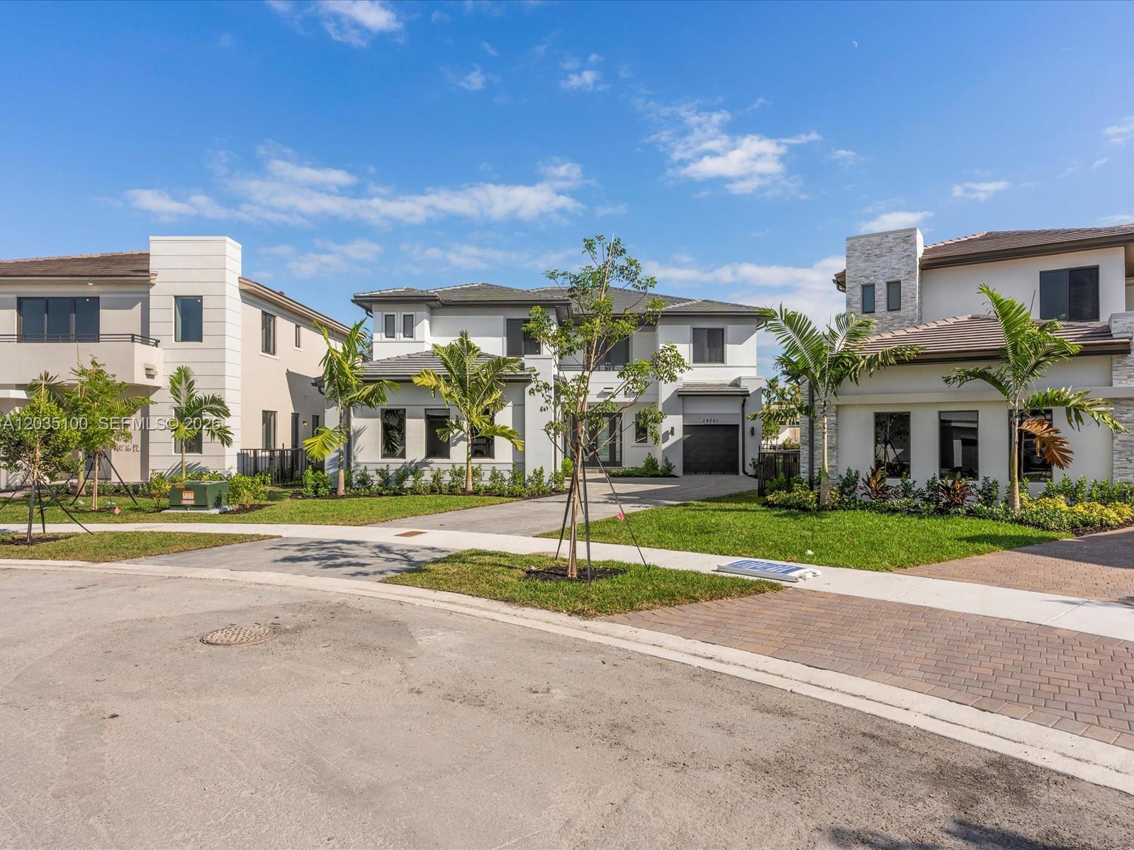 A street-level view shows three modern two-story houses with palm trees and manicured lawns — 19701 NE 16th Pl, Miami FL 33179, MIAMI, FL