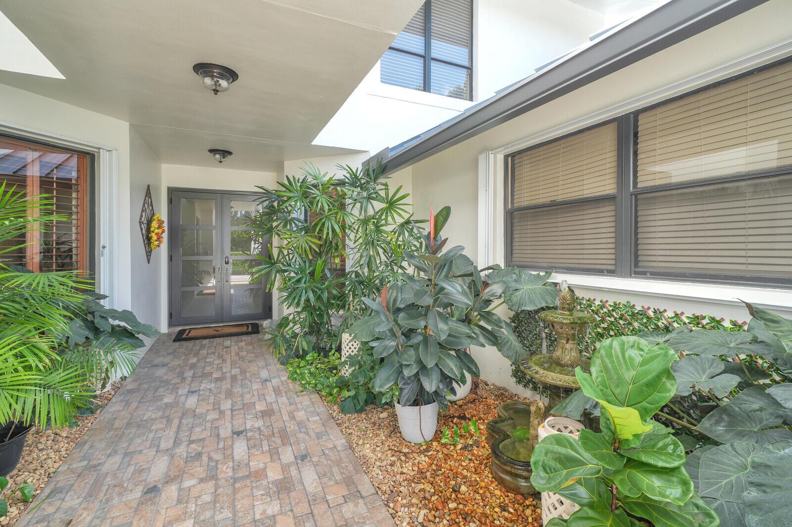 A two-story white house with a metal roof, two garages, and a palm tree — 181 Atlantis Boulevard # C, Atlantis FL 33462, ATLANTIS, FL