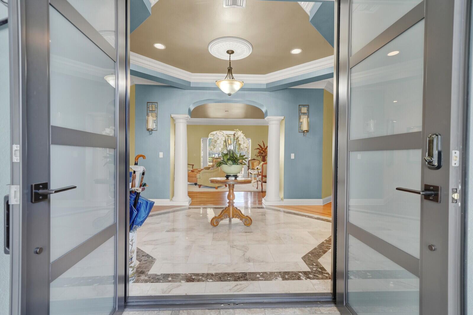 A paved walkway leads to a double-door entrance surrounded by potted plants and a fountain — 181 Atlantis Boulevard # C, Atlantis FL 33462, ATLANTIS, FL