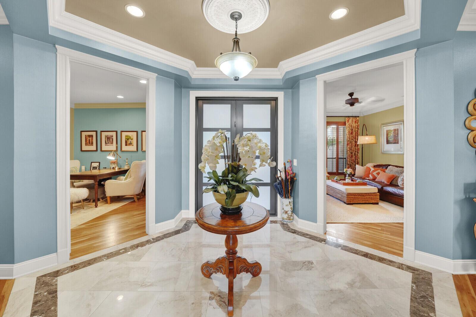 A foyer with marble flooring, a central pedestal table, and doorways leading to adjacent rooms — 181 Atlantis Boulevard # C, Atlantis FL 33462, ATLANTIS, FL