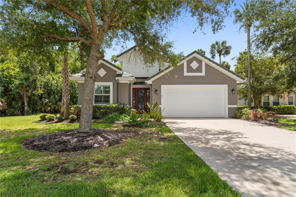 A single-story house with a white garage door, a red front door, and a large tree — 41 RIVERVIEW BEND N, PALM COAST, FL