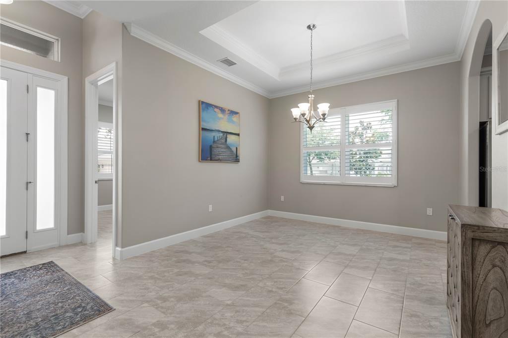 A dining room with tile flooring, a tray ceiling, a chandelier, and a wall painting — 41 RIVERVIEW BEND N, PALM COAST, FL