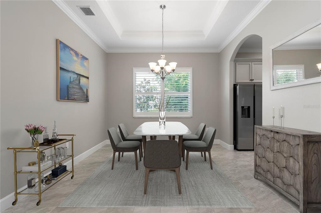A dining room features a white table, six gray chairs, a chandelier, and a sideboard — 41 RIVERVIEW BEND N, PALM COAST, FL