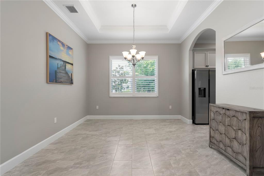 A dining room with a tray ceiling, chandelier, tile flooring, and a wooden sideboard — 41 RIVERVIEW BEND N, PALM COAST, FL