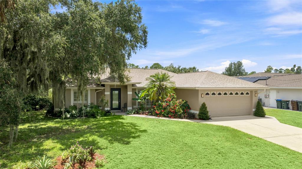 A single-story house with a tan exterior, a two-car garage, and a large front lawn — 2451 ALTOONA AVENUE, NORTH PORT, FL