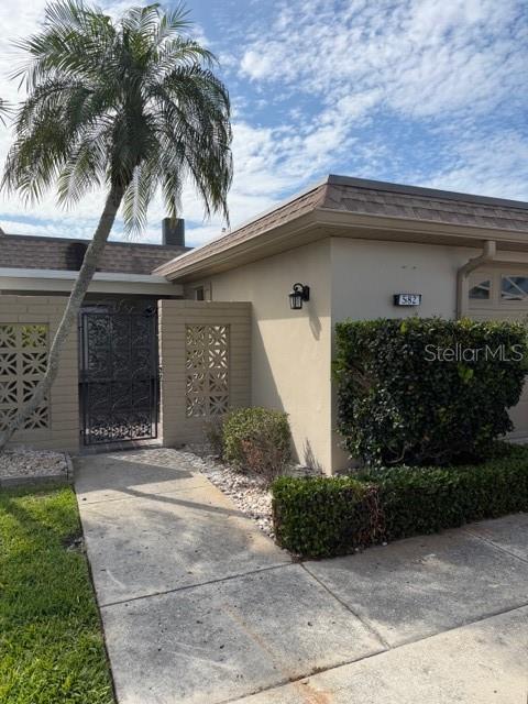 A concrete walkway leads to the entrance of a house with a decorative metal gate — 582 BOCA CIEGA POINT BOULEVARD N, ST PETERSBURG, FL