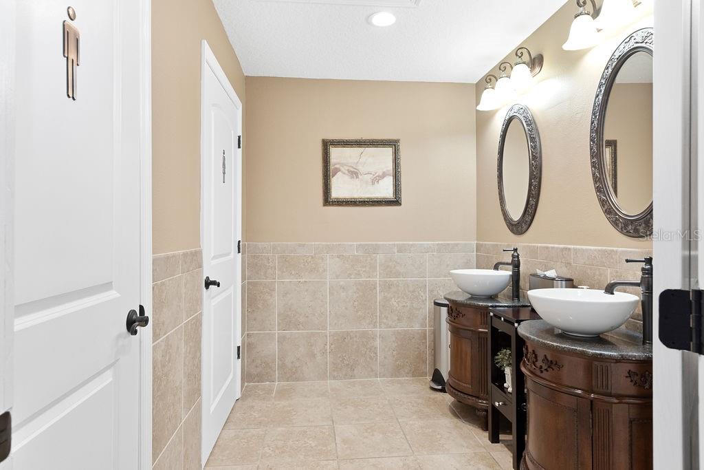 A bathroom features a double vanity with vessel sinks, oval mirrors, and tiled walls — 112 W INDIANA AVENUE UNIT 206, DELAND, FL