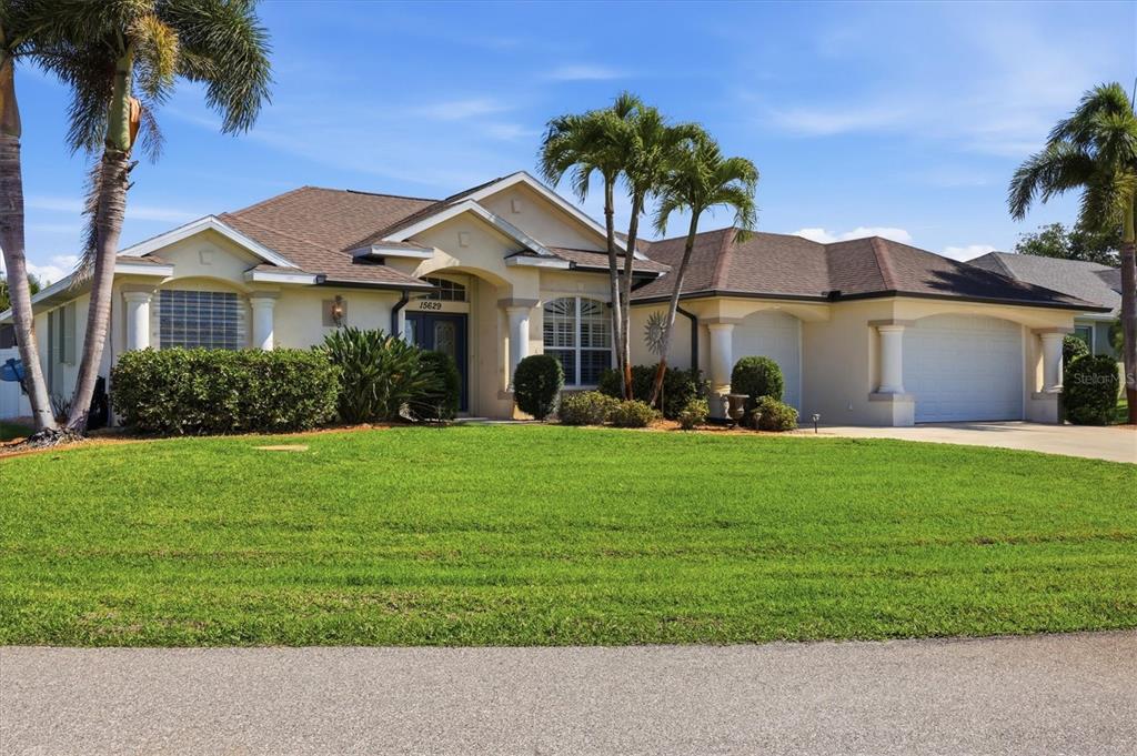 A single-story suburban house with a tan stucco exterior, brown roof, and palm trees — 15629 HAVANA CIRCLE, PORT CHARLOTTE, FL