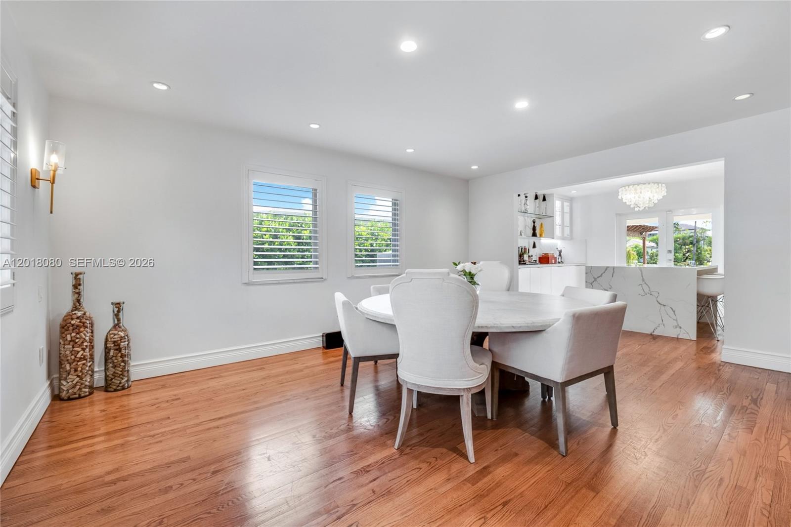 A dining room features a round marble table, white upholstered chairs, and hardwood floors — 13035 Nevada St, Coral Gables FL 33156, CORAL GABLES, FL