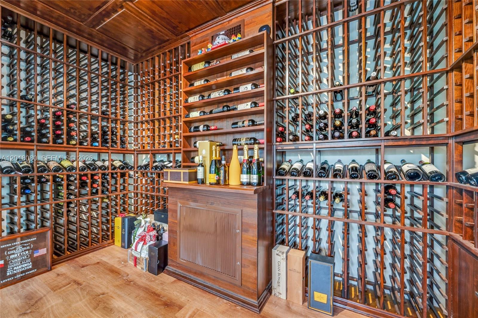 A wine cellar features extensive wooden racking, a central cabinet, and numerous bottles of wine — 13035 Nevada St, Coral Gables FL 33156, CORAL GABLES, FL