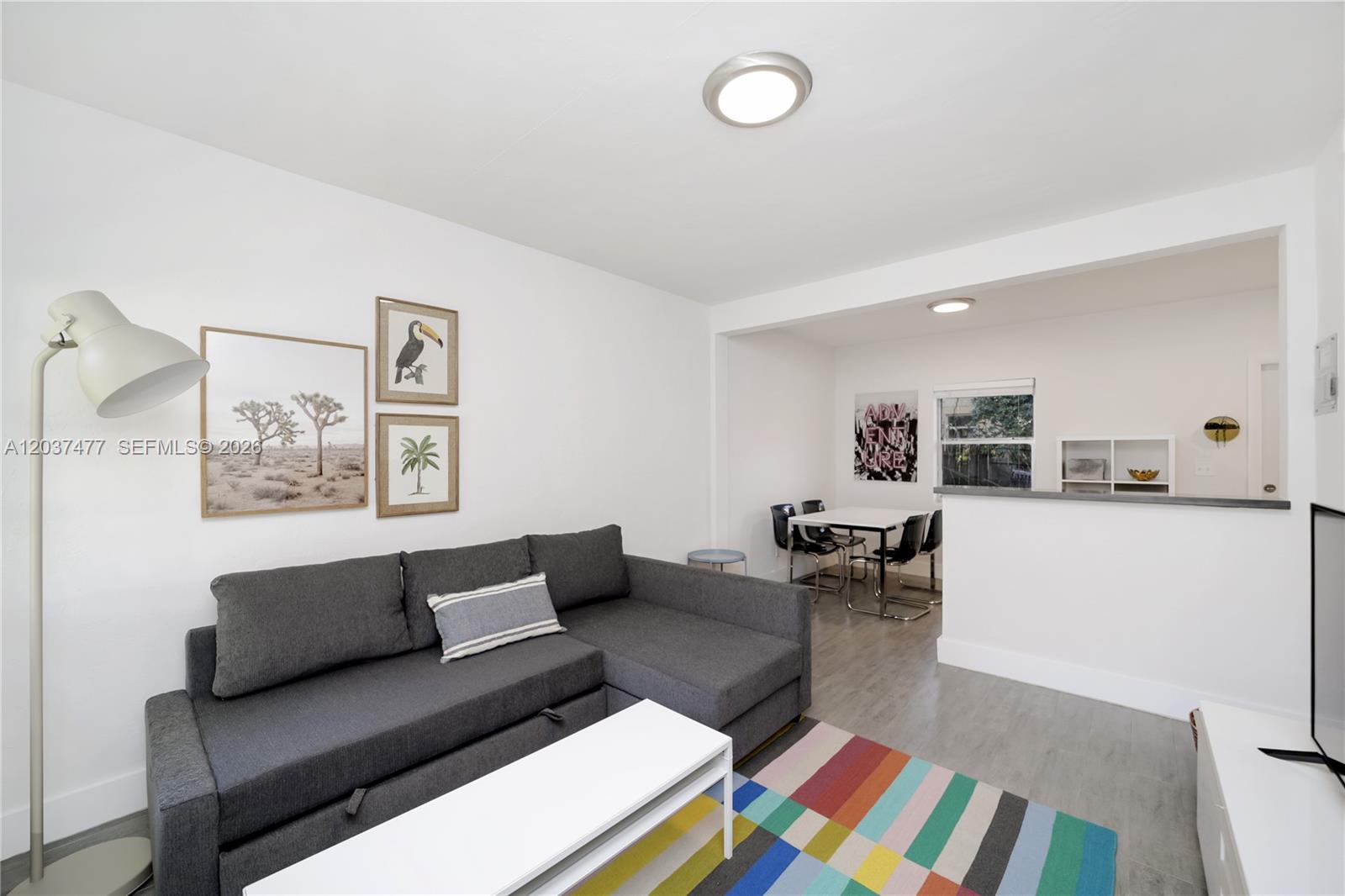 A living room features a grey sectional sofa, a colorful rug, and an adjacent dining area — 770 NE 123rd St # 24, North Miami FL 33161, NORTH MIAMI, FL