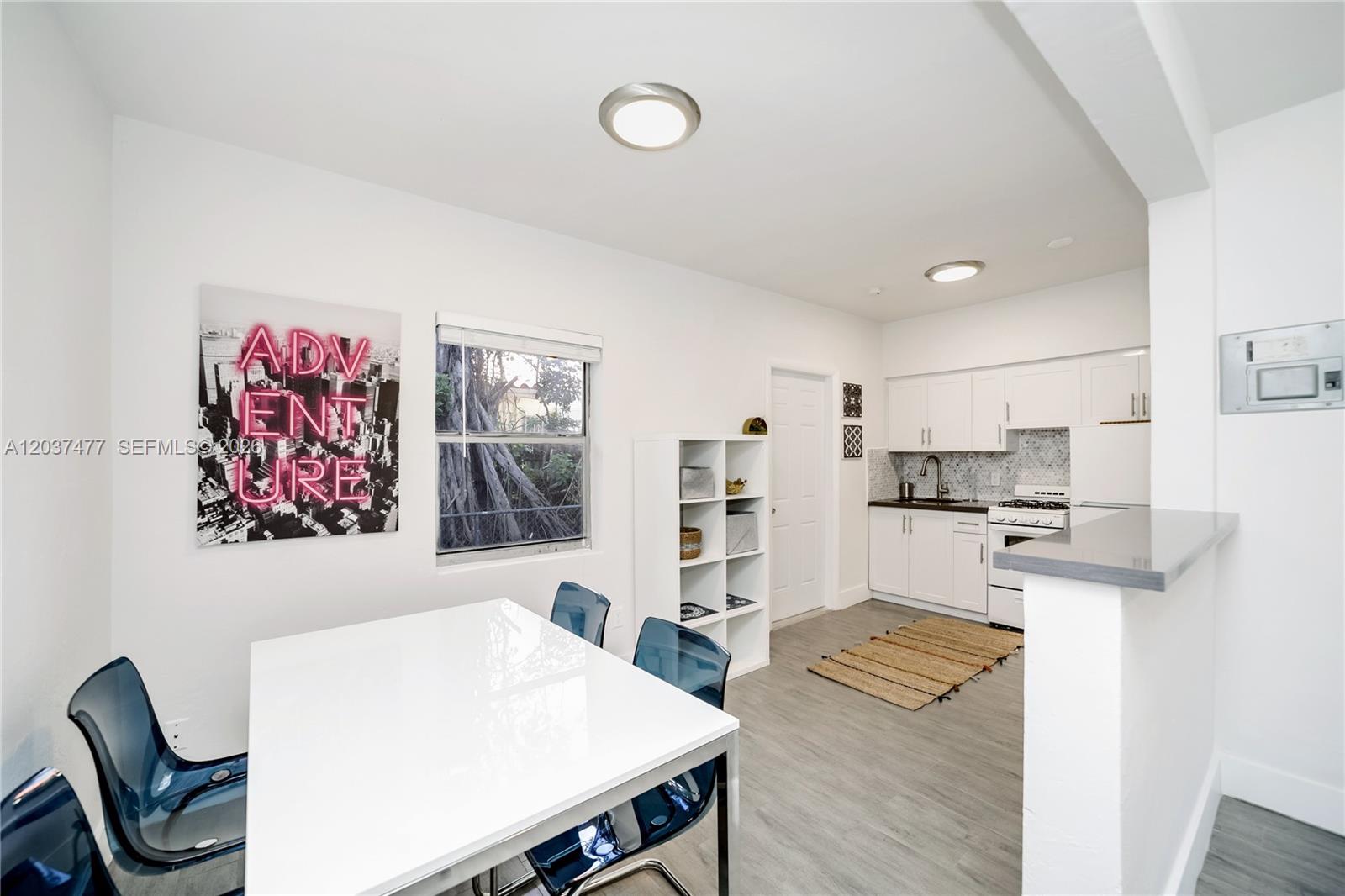 A kitchen and dining area features white cabinets, a white table, and blue chairs — 770 NE 123rd St # 24, North Miami FL 33161, NORTH MIAMI, FL