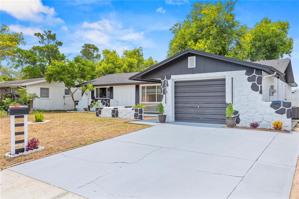 A single-story house with a white and black stone facade and a gray garage door — 6820 EL CAMINO PALOMA STREET, PORT RICHEY, FL