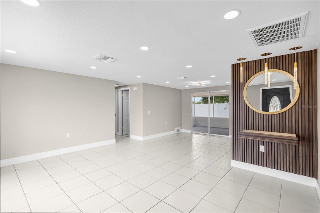 A living room with white tile floors, recessed lighting, and a wood-slatted accent wall feature — 6820 EL CAMINO PALOMA STREET, PORT RICHEY, FL