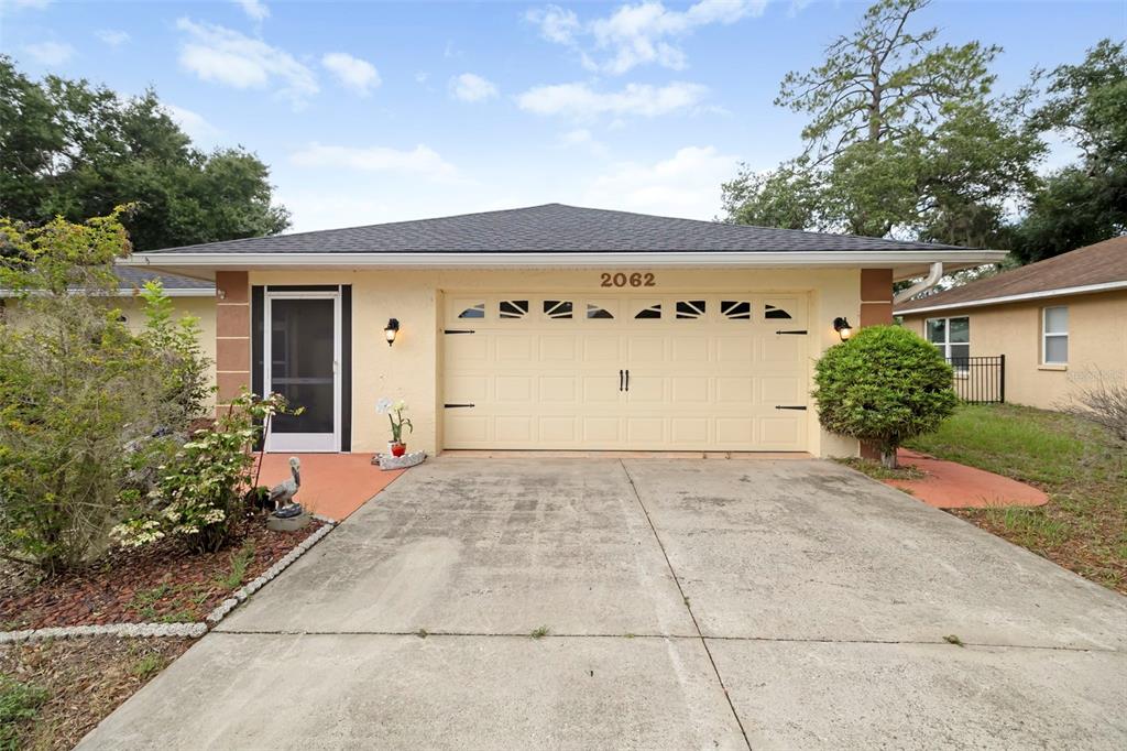 A single-story house with a beige stucco exterior, a two-car garage, and a concrete driveway — 2062 OLD ARBOR COURT, SARASOTA, FL