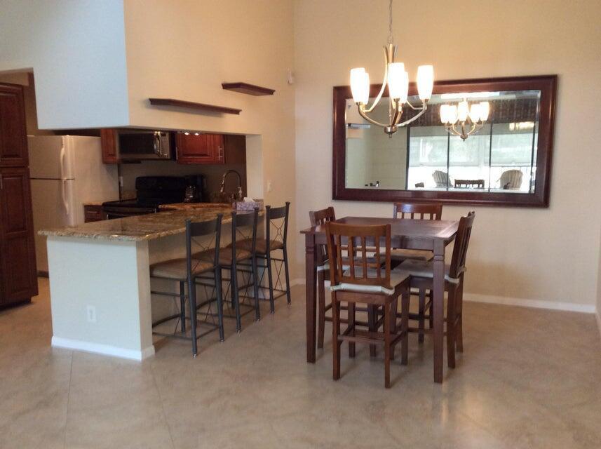 A dining area with a wooden table and chairs sits adjacent to a kitchen island — 812 Sky Pine Way # A3, FL 33415, FL