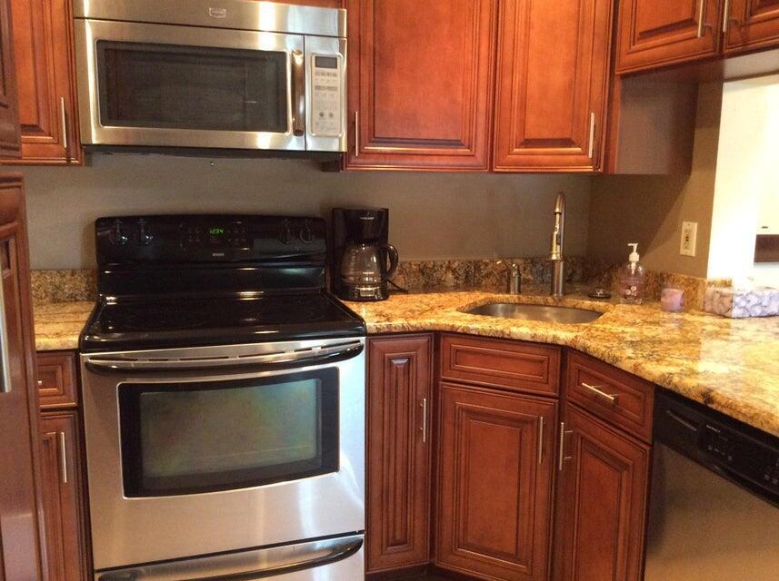 A kitchen with wood cabinets, granite countertops, and stainless steel appliances — 812 Sky Pine Way # A3, FL 33415, FL