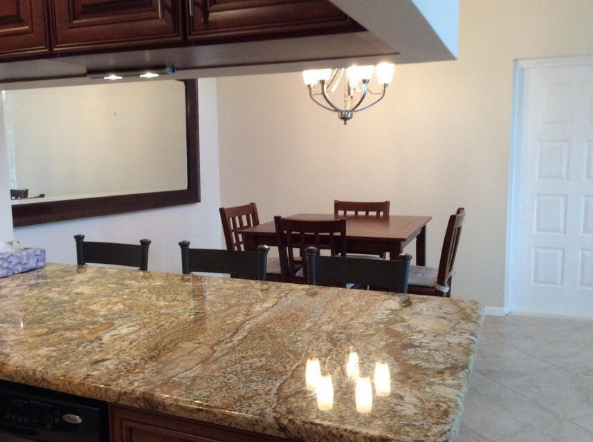 A kitchen island with granite countertops overlooks a dining area with a wooden table — 812 Sky Pine Way # A3, FL 33415, FL