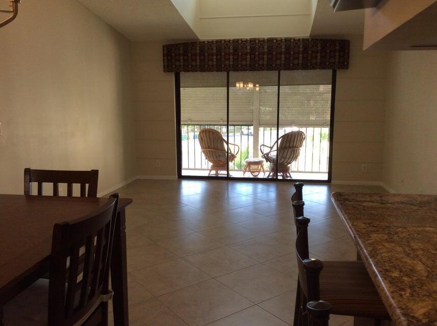 A dining area with tile floors, a kitchen island, and sliding glass doors to a balcony — 812 Sky Pine Way # A3, FL 33415, FL