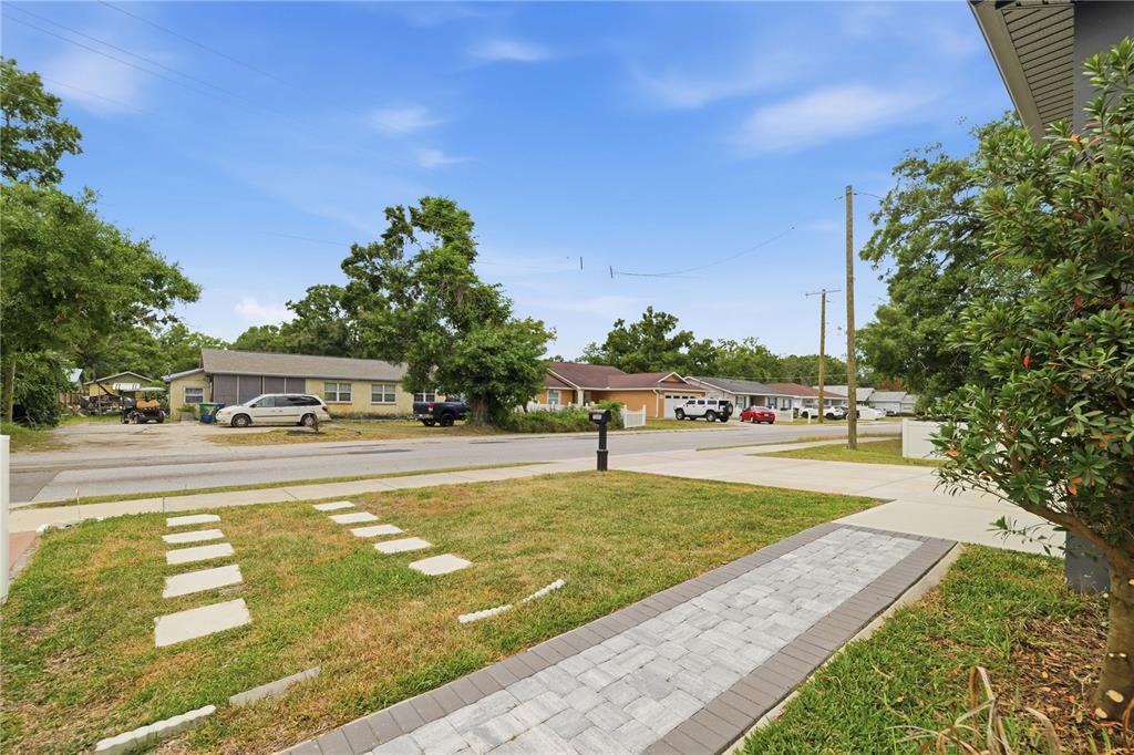 A paved walkway leads through a front lawn toward a street with houses and cars — 7505 N ROME AVENUE, TAMPA, FL
