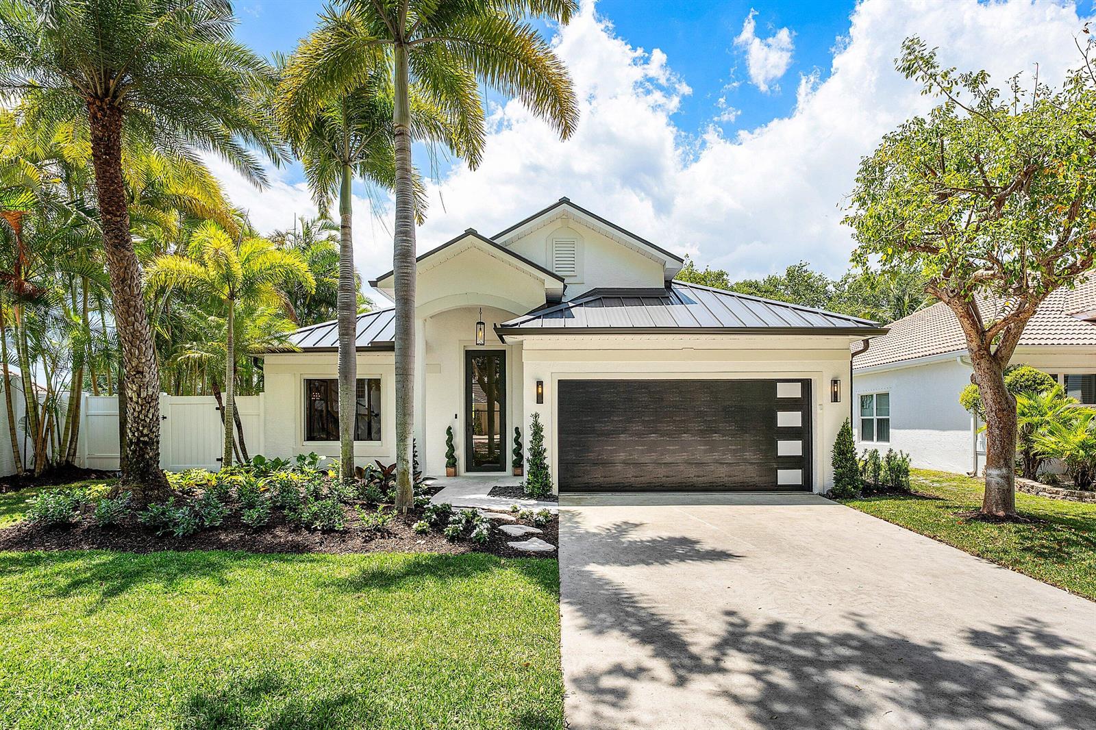 A single-story white house with a dark metal roof, palm trees, and a two-car garage — 1210 Delray Lakes Drive, Delray Beach FL 33444, DELRAY BEACH, FL