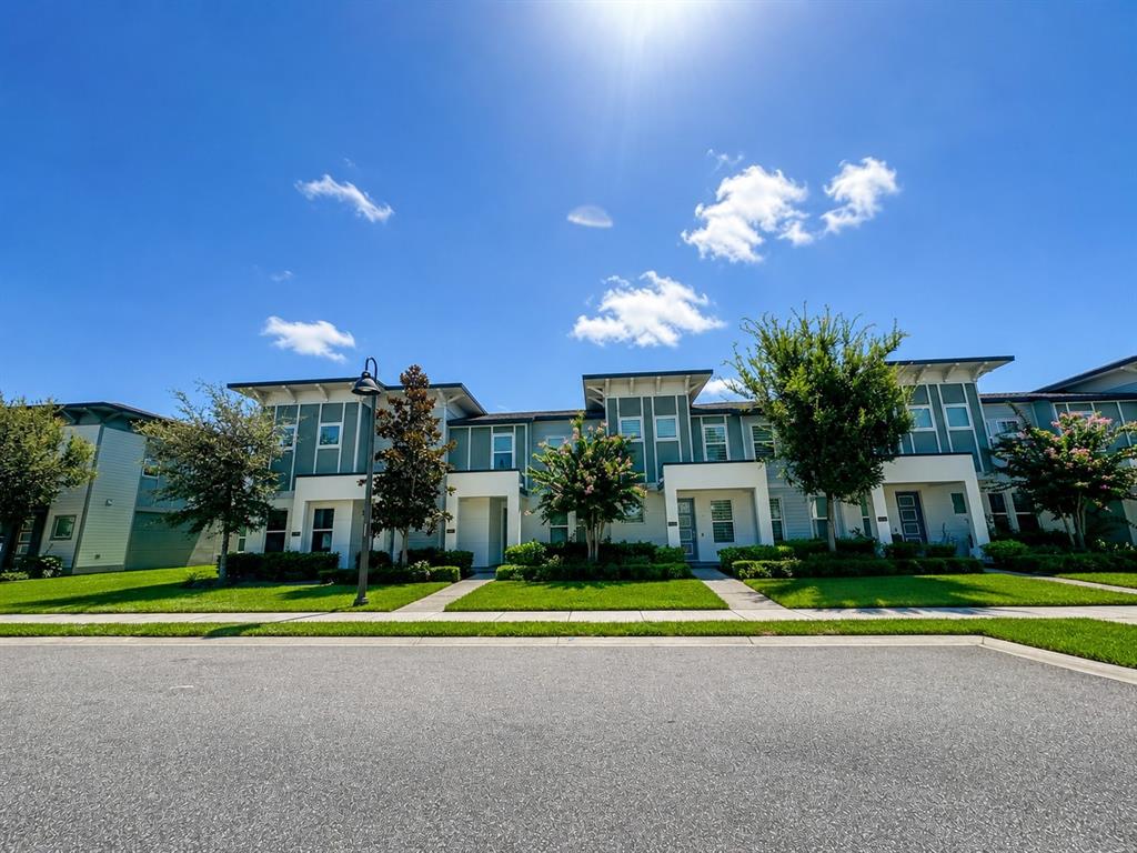 A row of two-story townhomes with light blue siding and white trim under a blue sky — 7248 CARRICKBEND LANE, ORLANDO, FL