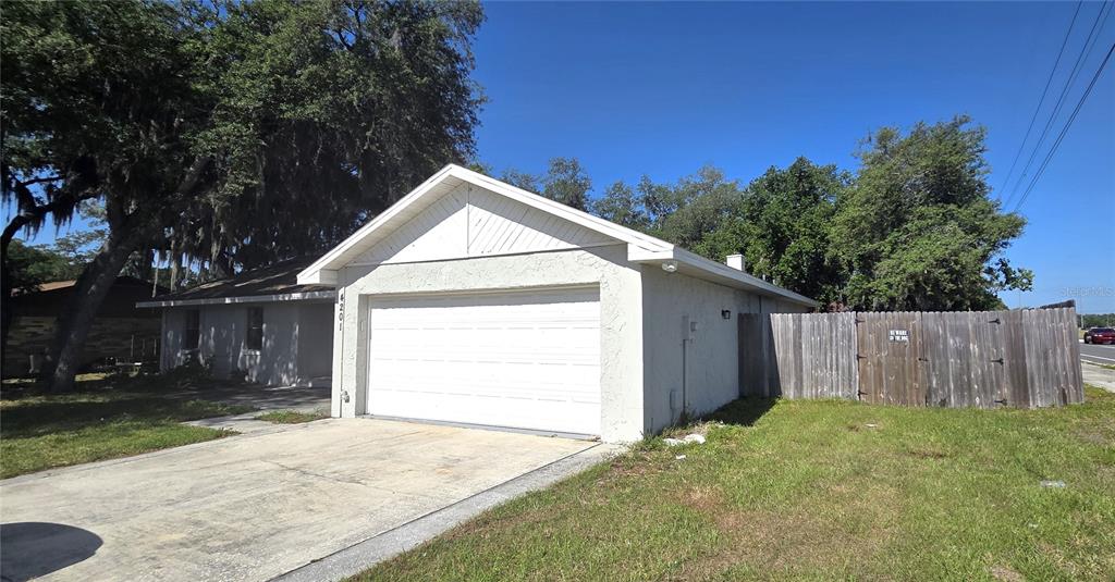 A single-story house with a white stucco exterior, a garage, and a wooden fence — 4201 SHADOW WOOD DRIVE, WINTER HAVEN, FL