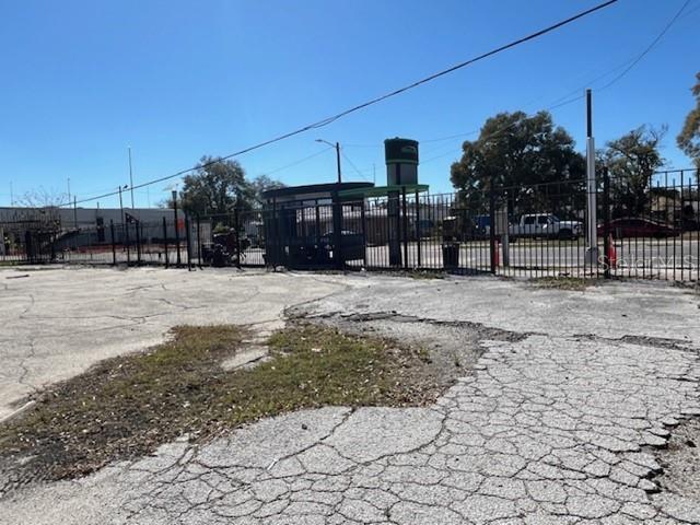 A cracked asphalt parking lot sits in front of a fenced-in bus stop shelter — 2305 N NEBRASKA AVENUE, TAMPA, FL