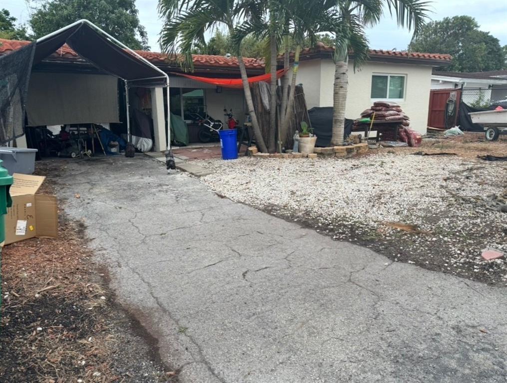 A cracked asphalt driveway leads to a house with a carport and gravel yard — 490 NW 29TH AVENUE, FORT LAUDERDALE, FL
