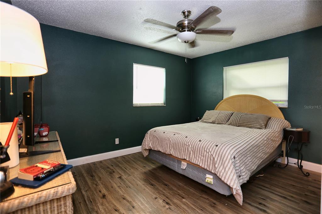 A bedroom with dark green walls, wood-look flooring, a ceiling fan, and a striped bedspread — 640 DEAN STREET, MULBERRY, FL