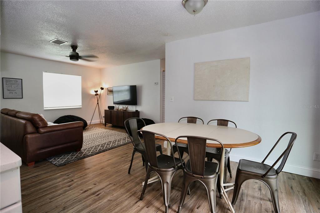 A dining area with a metal table and chairs sits adjacent to a living room — 640 DEAN STREET, MULBERRY, FL