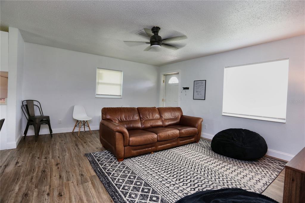 A living room features a brown leather sofa, a patterned rug, and wood-look flooring — 640 DEAN STREET, MULBERRY, FL