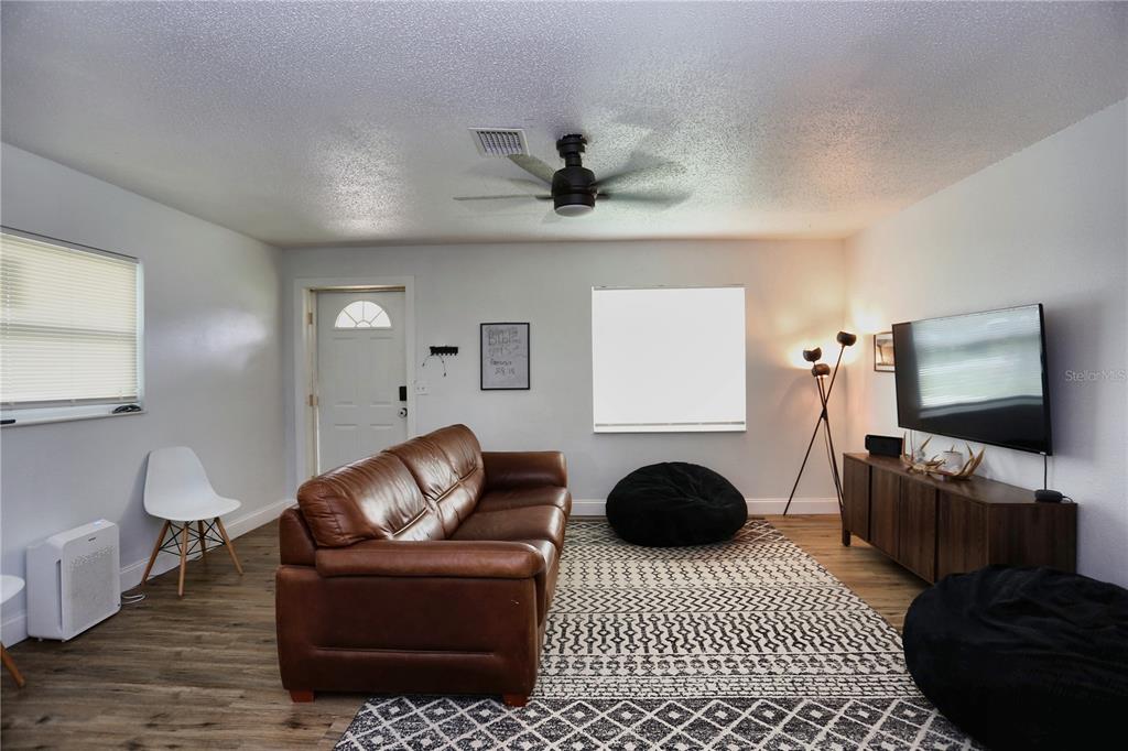A living room features a brown leather sofa, a patterned area rug, and a television — 640 DEAN STREET, MULBERRY, FL