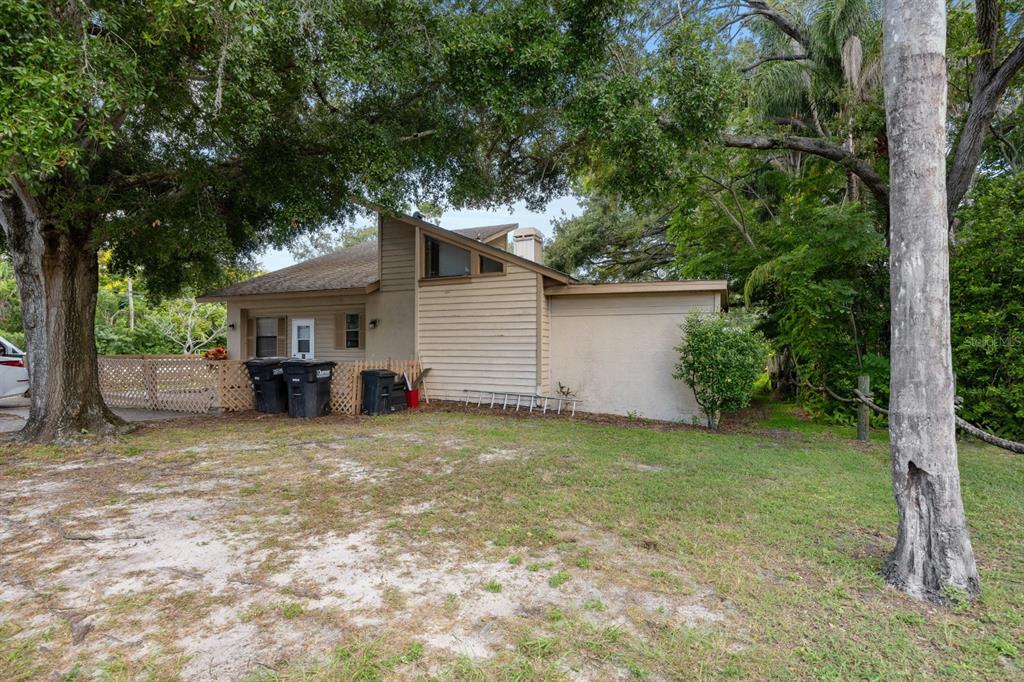 A tan house with a unique angular roofline sits behind a large tree and lawn — 2700 STATE ROAD 590, CLEARWATER, FL